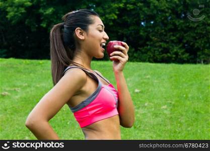 Fit young woman eating an apple