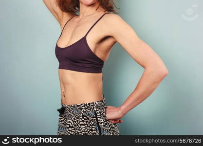 Fit young woman in shorts and sports bra is showing off her toned stomach