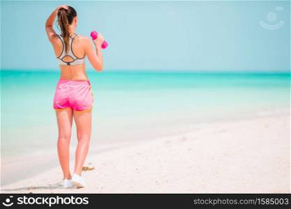 Fit young woman on the tropical beach in sportswear. Fit young woman doing exercises on tropical white beach in her sportswear