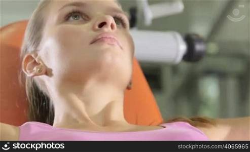 Fit young woman training in health fitness club on chest press machine closeup