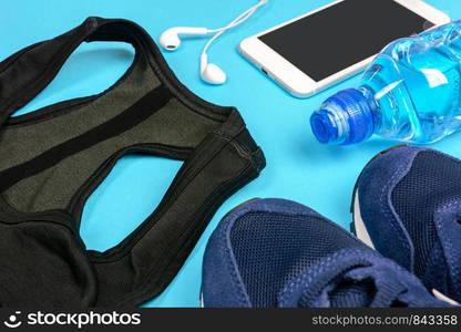 Fitness activity concept - composition of some personal sport accessories for a runner woman on a blue background.