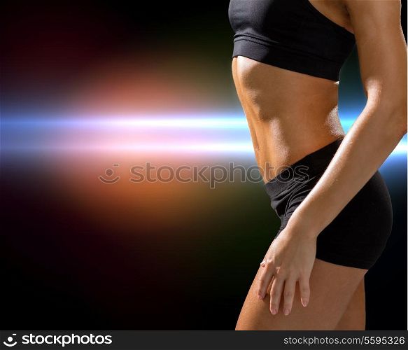 fitness and diet concept - close up of beautiful athletic female abs in sportswear