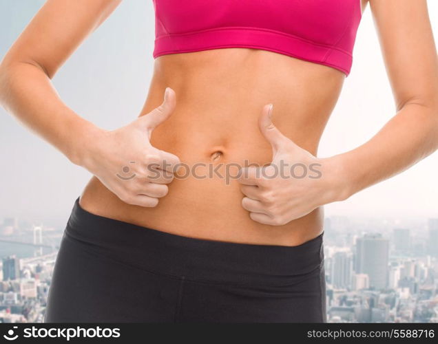 fitness and diet concept - close up of female abs and hands showing thumbs up