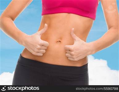 fitness and diet concept - close up of female abs and hands showing thumbs up