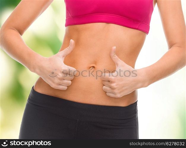 fitness and diet concept - close up of female abs and hands showing thumbs up