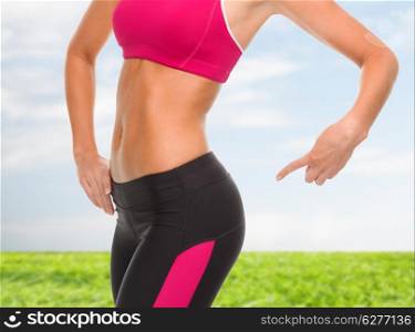 fitness and diet concept - close up of sporty woman pointing at her buttocks