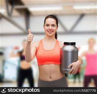 fitness and diet concept - smiling teenage girl with jar of protein showing thumbs up