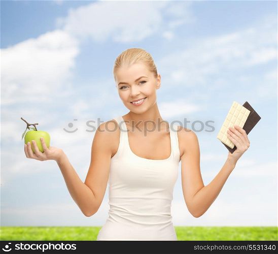 fitness and diet concept - sporty woman with apple and chocolate bars