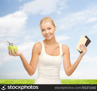 fitness and diet concept - sporty woman with apple and chocolate bars