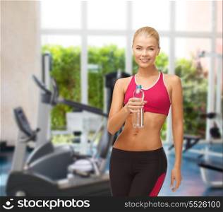 fitness and gym concept - sporty woman with bottle of water at gym