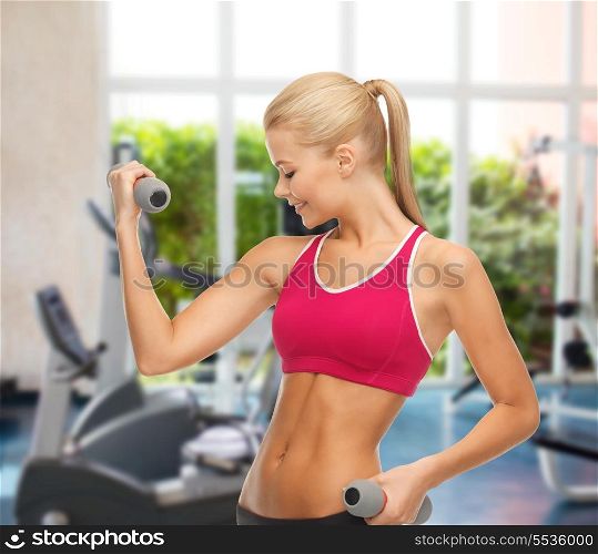 fitness and gym concept - young sporty woman with light dumbbells at gym