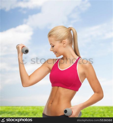 fitness and health concept - young sporty woman with light dumbbells outdoors