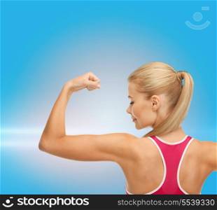 fitness and healthcare concept - young sporty woman showing her biceps