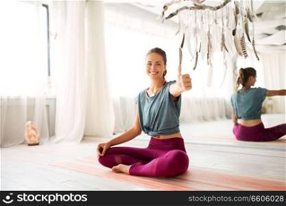 fitness and healthy lifestyle concept - happy smiling woman showing thumbs up at yoga studio. smiling woman showing thumbs up at yoga studio