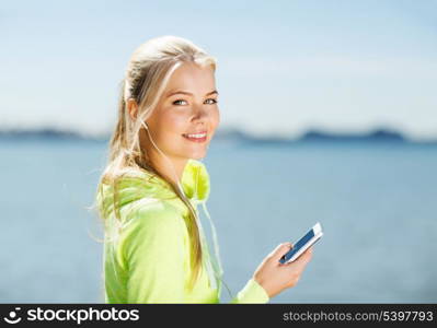 fitness and lifestyle concept - woman doing sports and listening to music outdoors