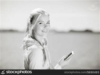 fitness and lifestyle concept - woman doing sports and listening to music outdoors