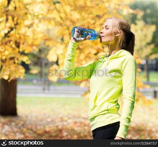 fitness and lifestyle concept - woman drinking water after doing sports outdoors