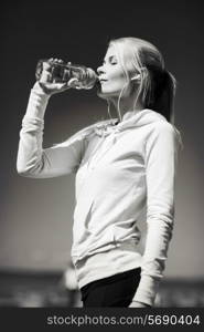 fitness and lifestyle concept - woman drinking water after doing sports outdoors