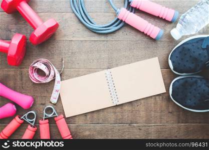 Fitness and weight loss concept, dumbbells, jump rope and measuring-tape on wooden background, Top view