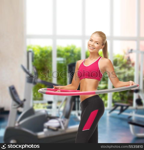 fitness ang gym concept - young sporty woman with hula hoop at gym