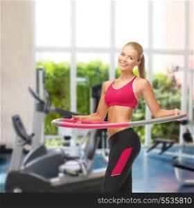 fitness ang gym concept - young sporty woman with hula hoop at gym