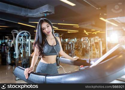 Fitness Asian women performing doing exercises training the run on treadmill in sport gym interior and health club.