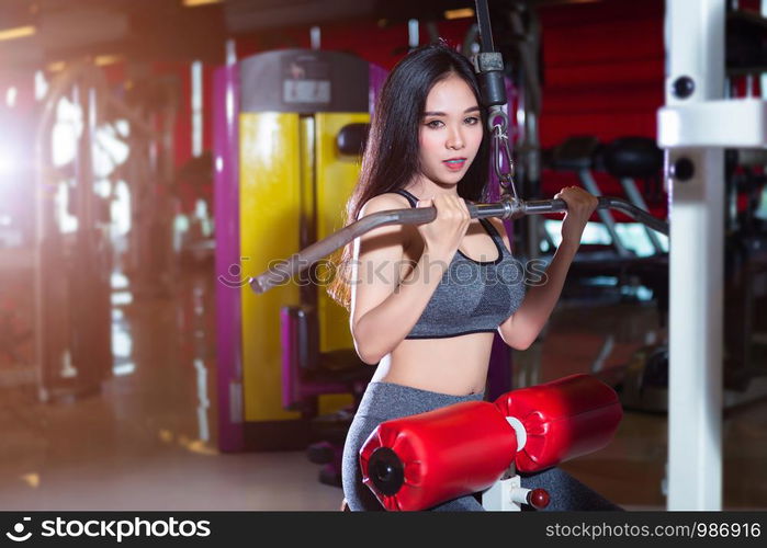 Fitness Asian women performing doing exercises training the shoulder and chest muscles in sport gym interior and health club.