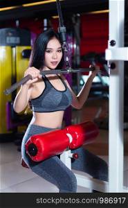Fitness Asian women performing doing exercises training the shoulder and chest muscles in sport gym interior and health club.