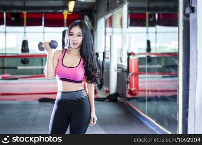 Fitness Asian women performing doing exercises training with dumbbell sport in sport gym interior and fitness health club with sports exercise equipment Gym background.