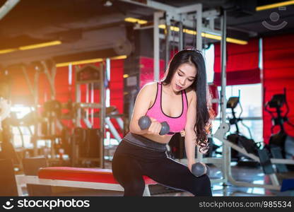 Fitness Asian women performing doing exercises training with dumbbell sport in sport gym interior and fitness health club with sports exercise equipment Gym background.