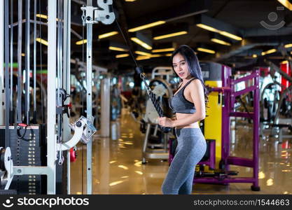 Fitness Asian women performing doing exercises training with rowing machine (Seat Cable Rows Machine) in sport gym interior and fitness health club with sports exercise equipment Gym background.