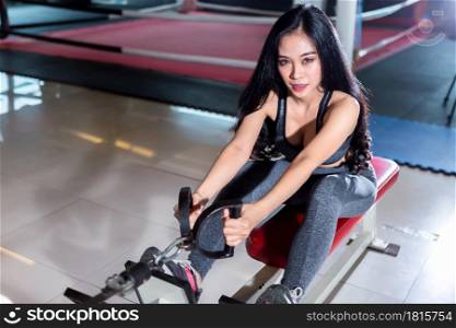 Fitness Asian women performing doing exercises training with rowing machine (Seat Cable Rows Machine) in sport gym interior and fitness health club is Public places with sports exercise equipment Gym.