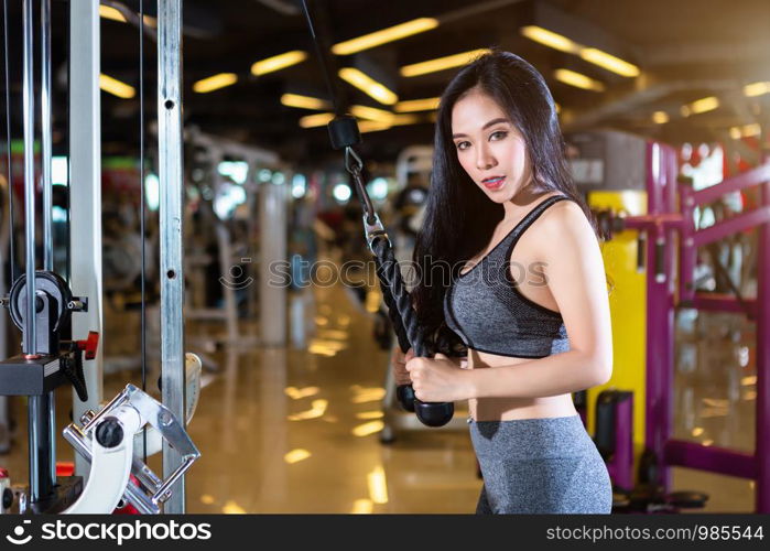 Fitness Asian women performing doing exercises training with rowing machine (Seat Cable Rows Machine) in sport gym interior and fitness health club with sports exercise equipment Gym background.