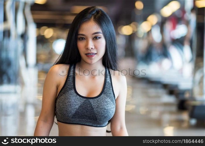 Fitness Asian women sitting in sport gym interior and fitness health club with sports exercise equipment Gym background.