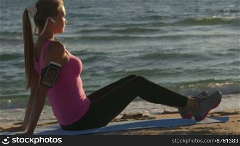 Fitness athletic girl exercising on the beach at sunset