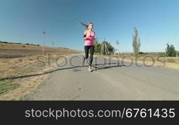 Fitness athletic girl jogging along the road during outdoor workout wide angle