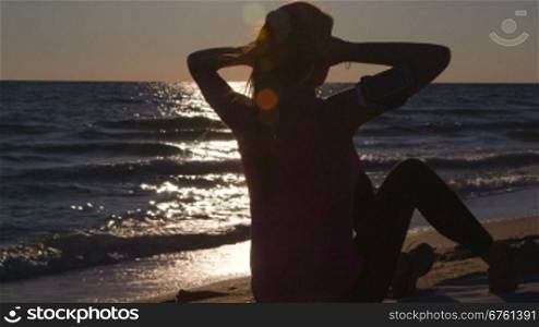 Fitness athletic woman doing abdominal crunch during workout on the beach at sunset