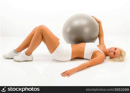 Fitness blonde woman exercising with gym ball lying white floor