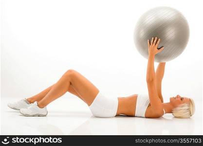 Fitness blonde woman exercising with Pilates ball lying white floor