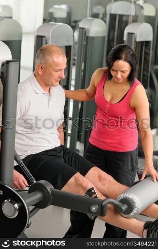 Fitness center active man exercising legs with personal trainer