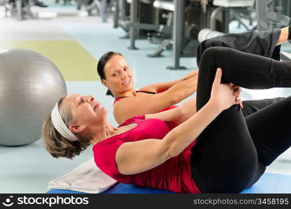 Fitness center senior woman exercise sit ups with personal trainer