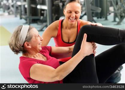 Fitness center senior woman exercise sit ups with personal trainer