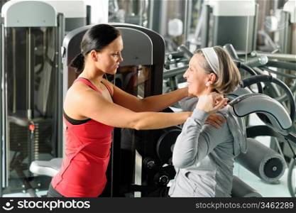 Fitness center senior woman exercise with personal trainer on machine