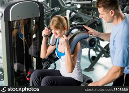 Fitness center young woman exercise with personal trainer on gym machine