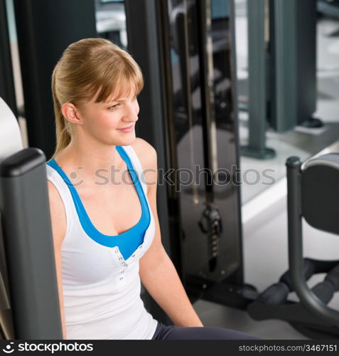 Fitness center young woman sitting on gym machine workout