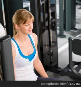 Fitness center young woman sitting on gym machine workout