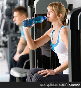 Fitness club young woman relax at weight machine drink water