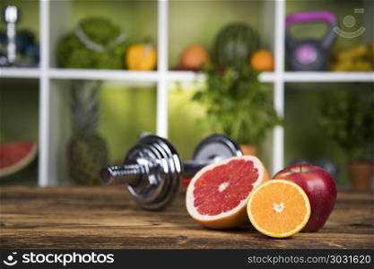 Fitness concept with dumbbells and fresh fruits. Diet and fitness, dumbbell with vitamin