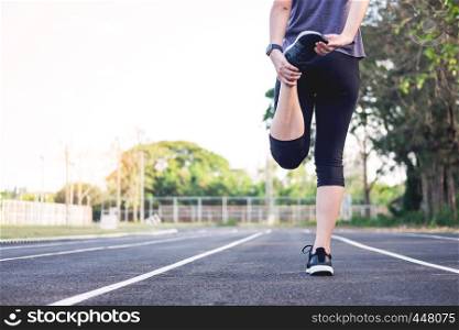 Fitness concept. Young fitness woman stretching legs and preparing to run on the floor at stadium.