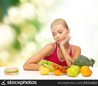 fitness, diet and food concept - doubting woman with fruits and hamburger